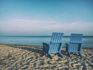 two blue beach chairs near body of water by Aaron Burden courtesy of Unsplash.