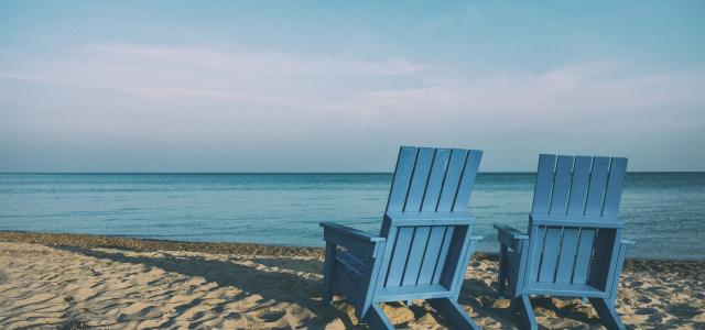 two blue beach chairs near body of water by Aaron Burden courtesy of Unsplash.